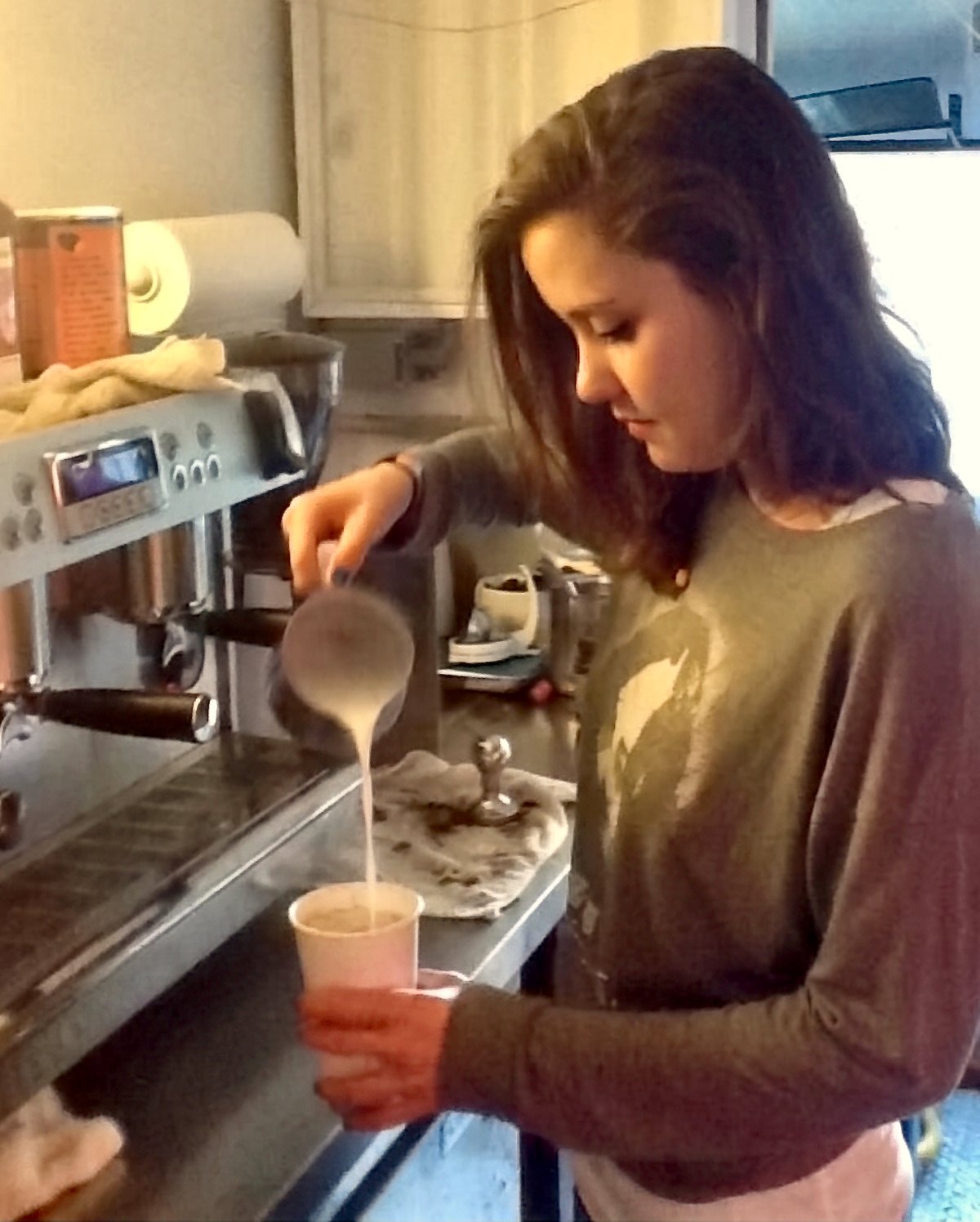 An Espresso Subito barista pouring steamed milk into a cup inside the coffee truck