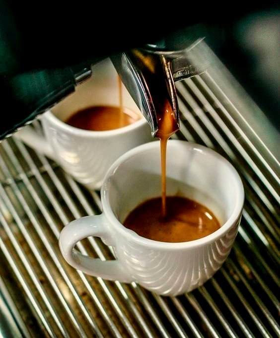 Two espressos pulling into white cups on the machine