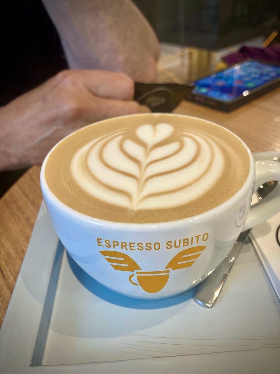 A latte with heart art in a branded Espresso Subito cup