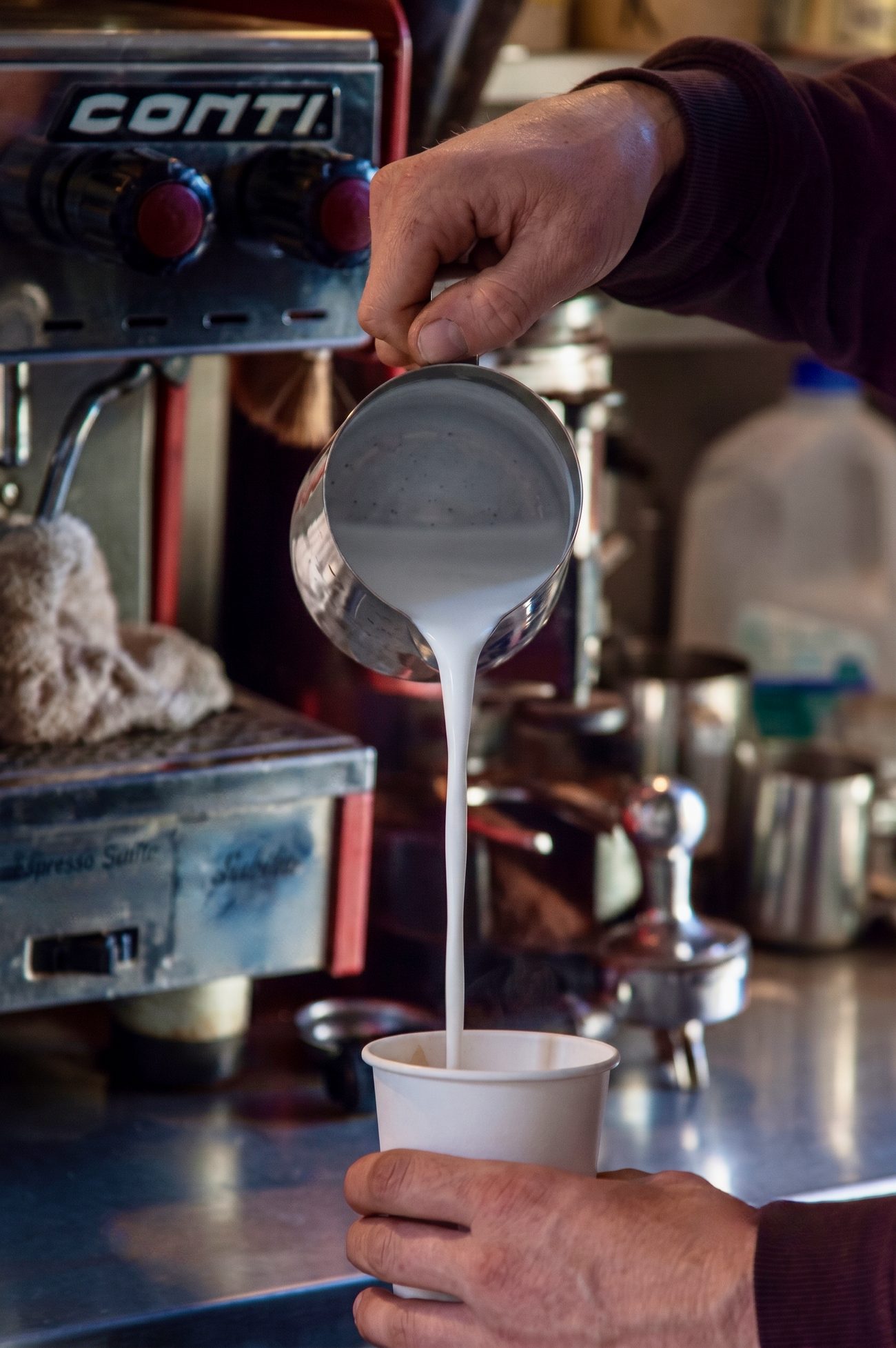 A barista pouring steamed milk into a cup at the Espresso Subito bar