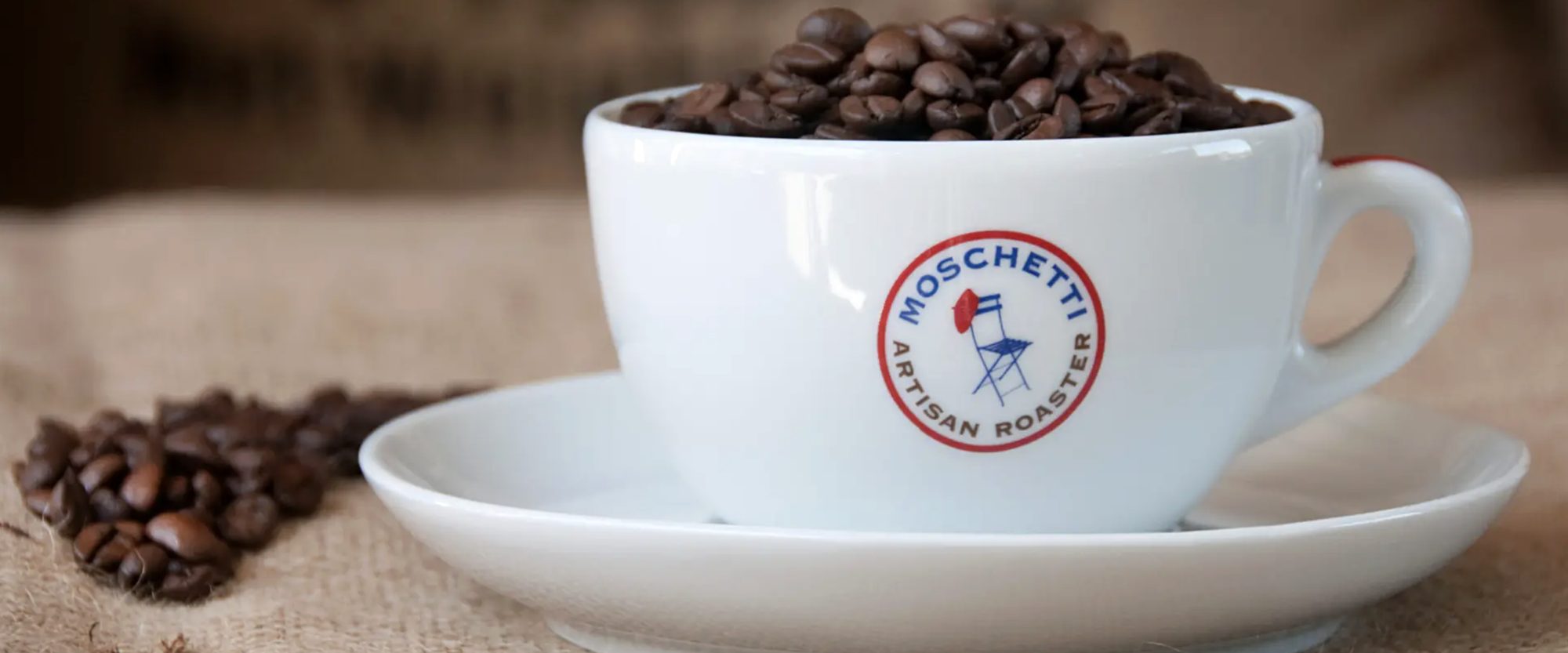 A Moschetti Artisan Roaster cup filled with fresh coffee beans